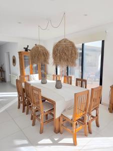 a dining room with a white table and chairs at COSTA ESMERALDA S3 para 10 pileta y jardín privados in Pinamar