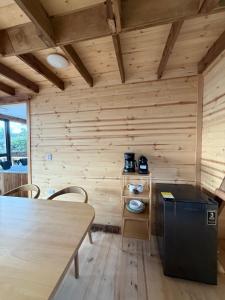 a room with a wooden wall with a table and a refrigerator at Monte Waïa in Guasca