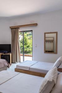 a bedroom with two beds and a mirror and a window at B&B Sunny Side in Sarandë