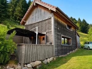a wooden house with an umbrella on the side of it at Le Cabanon de LaFermeDuNol in La Bresse