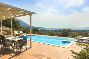 a patio with a table and chairs next to a swimming pool at Villa Dora in Kefallonia