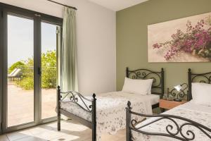 a bedroom with two beds and a sliding glass door at Villa Dora in Kefallonia +25 photos