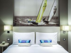a bedroom with a bed with a picture of sailboats at Mercure Pattaya Ocean Resort in Pattaya +57 photos