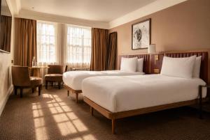 a hotel room with two beds and a table at The May Fair Hotel, Mayfair, London in London