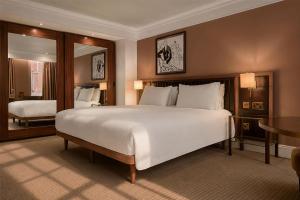 a bedroom with a large white bed and a mirror at The May Fair Hotel, Mayfair, London in London +48 photos