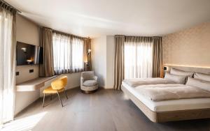 a bedroom with a bed and a desk and a chair at Avita suites Ortisei in Ortisei