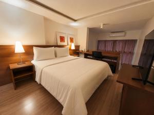 a hotel room with a large bed and a desk at Hotel Habitare in Nova Friburgo
