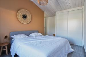a bedroom with a large white bed and a wall at L'Épine - Maison lumineuse - 300m de la plage in LʼÉpine