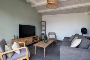 a living room with two couches and a flat screen tv at L'Épine - Maison lumineuse - 300m de la plage in LʼÉpine