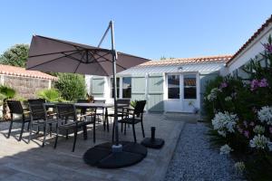a patio with a table and chairs and an umbrella at L'Épine - Maison lumineuse - 300m de la plage in LʼÉpine