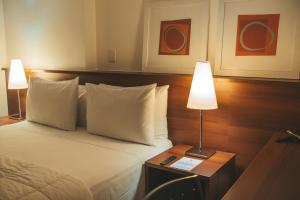 a bedroom with a bed with two lamps on a table at Hotel Habitare in Nova Friburgo