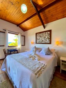 ein Schlafzimmer mit einem weißen Bett und einer Holzdecke in der Unterkunft Chalés Nascer da Lua in Monte Verde + 84 Fotos