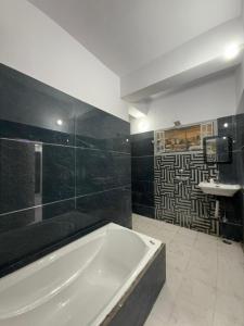 a large bathroom with a tub and a sink at Roshan's INN Hotel in Patna