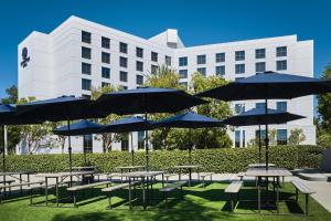 a group of tables with umbrellas in front of a building at DoubleTree by Hilton Irvine Spectrum in Irvine