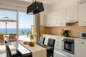 a kitchen with a table and a view of the ocean at Villa George by Villa Select in Lourdata