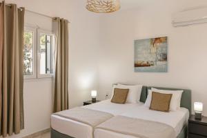 a white bedroom with a bed and a window at Villa George by Villa Select in Lourdata +14 photos