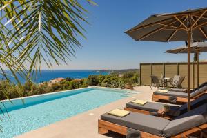 a swimming pool with chairs and an umbrella at Villa George by Villa Select in Lourdata