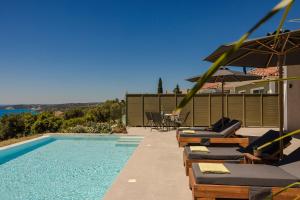 a swimming pool with lounge chairs and umbrellas next to at Villa George by Villa Select in Lourdata