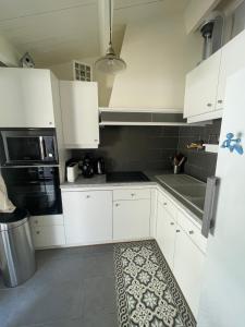 a kitchen with white cabinets and a stove top oven at Maison de Vacances des Centaurées in La Guérinière +6 photos