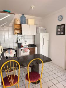 a kitchen with two chairs and a table and a refrigerator at Flat em Sao Jose da Coroa Grande in São José da Coroa Grande