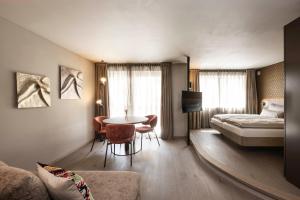 a hotel room with a bed and a table and chairs at Avita suites Ortisei in Ortisei +9 photos