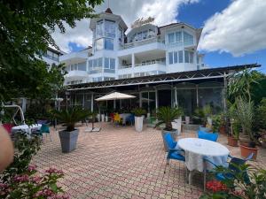 a large white building with blue chairs and tables at Hotel Kamelia in Varna City