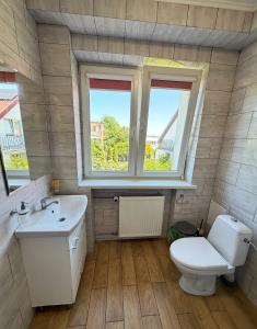 a bathroom with a toilet and a sink and two windows at Górna Residence&Rooms in Grudziądz +30 photos
