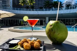 a drink and a plate of food on a table near a pool at Hotel Nacional in Rio de Janeiro
