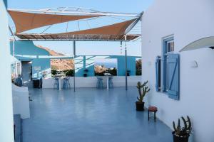 a white building with a patio with a brown umbrella at il Centro in Ios Chora