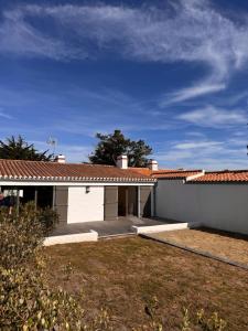 a white house with a roof and a yard at Maison de Vacances des Centaurées in La Guérinière