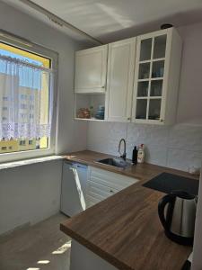 a kitchen with white cabinets and a sink and a window at Brzęczki Apart 2 in Mysłowice