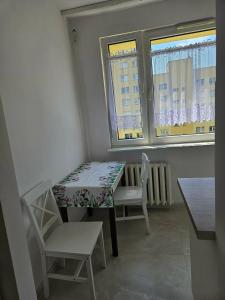 a table and chairs in a room with two windows at Brzęczki Apart 2 in Mysłowice