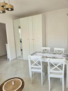 a white dining room with a white table and chairs at Brzęczki Apart 2 in Mysłowice