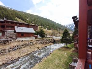 a river in front of a building with a mountain at AC Apartaments Vall d'Incles in Incles