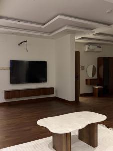 a living room with a table and a flat screen tv at STAYs ستايز in Medina