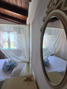 a mirror reflecting a bedroom with a bed and a window at Aligia Chalet in Nebida +52 photos