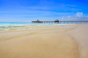 a sandy beach with a pier in the ocean at Little EsCape in Matlacha +25 photos