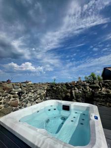 a hot tub sitting on top of a stone wall at Butterlump Cottage in Glastry
