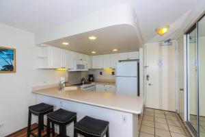 a kitchen with white cabinets and a white refrigerator at Ilikai Marina 382 in Honolulu