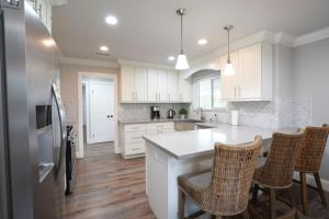 a kitchen with white cabinets and a counter with chairs at 4 bedroom, 3 bathrooms Pool Home in Orange