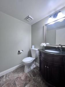 a bathroom with a toilet and a sink and a mirror at Luxurious 2 Bedroom Condo Shortest Walk To Disney in Anaheim
