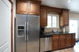 a kitchen with a stainless steel refrigerator and wooden cabinets at Charming Anaheim Home 1/2 Mile Walk to Disney in Anaheim