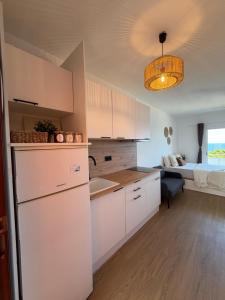 a kitchen with white cabinets and a room with a bed at LĀ KAI - Piso Carabelas in Candelaria