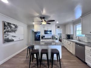 a kitchen with a island with stools and a ceiling fan at Anaheim California, Beautiful Pool Home, Short Walk to Disney in Anaheim