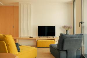 a living room with a tv and a couch and chairs at Rutlla 10 in Girona