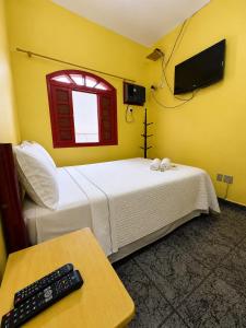 a bedroom with a bed and a window and a remote control at Sea Blue Suites in Angra dos Reis