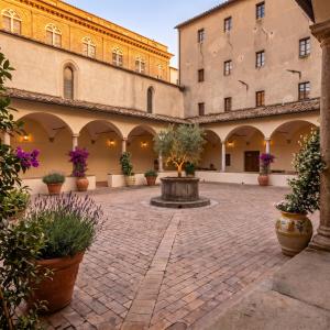 a courtyard with a fountain in the middle of a building at Relais Cloister Pienza in Pienza