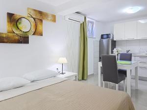a bedroom with a bed and a desk and a kitchen at House Gorica 2 - underground level apartments in Baška