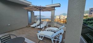 a balcony with white chairs and an umbrella at Lux Apartment Vidovic II in Rafailovici