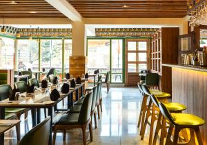 a dining room with tables and chairs and windows at The Willows Hotel, Bhutan in Thimphu
